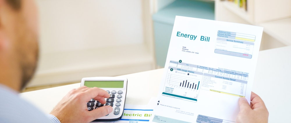 Man calculating electric bill statement and home energy consumption