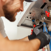 Closeup of plumber using screwdriver while installing new steel hot water central heating system in apartmen